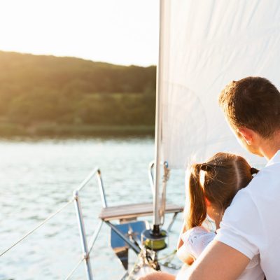 Weekend On Yacht. Family Embracing Enjoying Sailboat Tour Sitting On Deck Sailing In Sea. Rear View, Copy Space